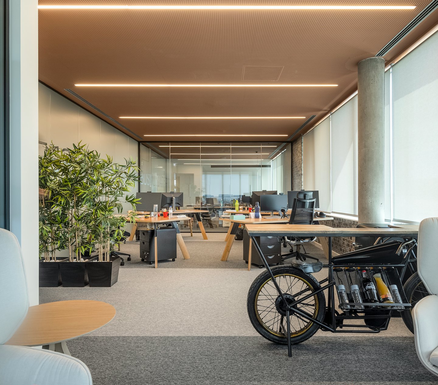 Modern office with unique motorcycle desk and plants.