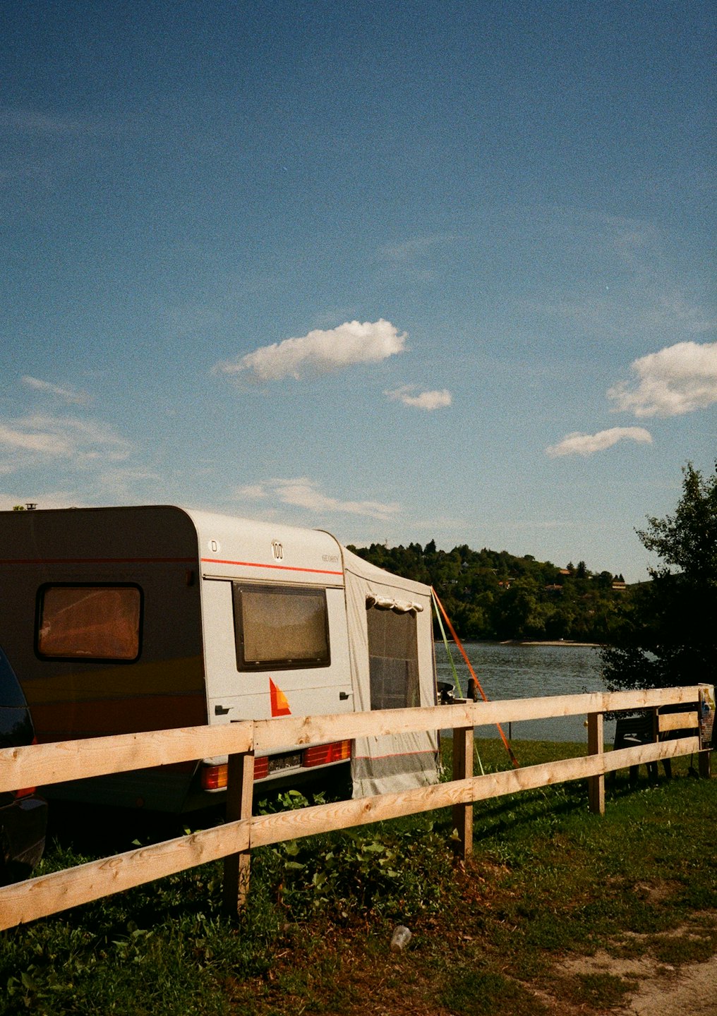 White caravan parked on grass by a lake.