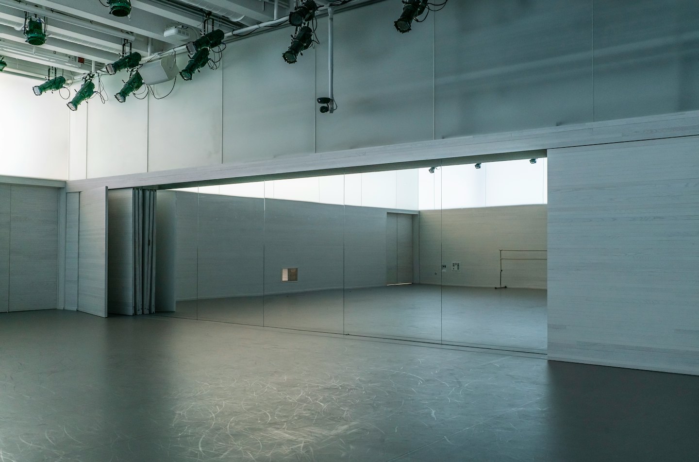 Empty dance studio with mirrored wall and ballet barre.