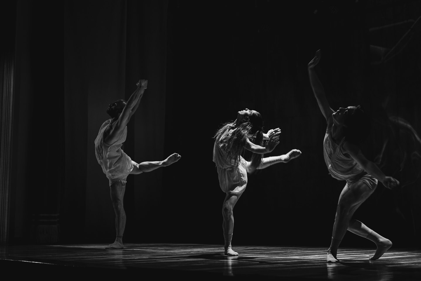 Three dancers perform dynamic movements on a stage.