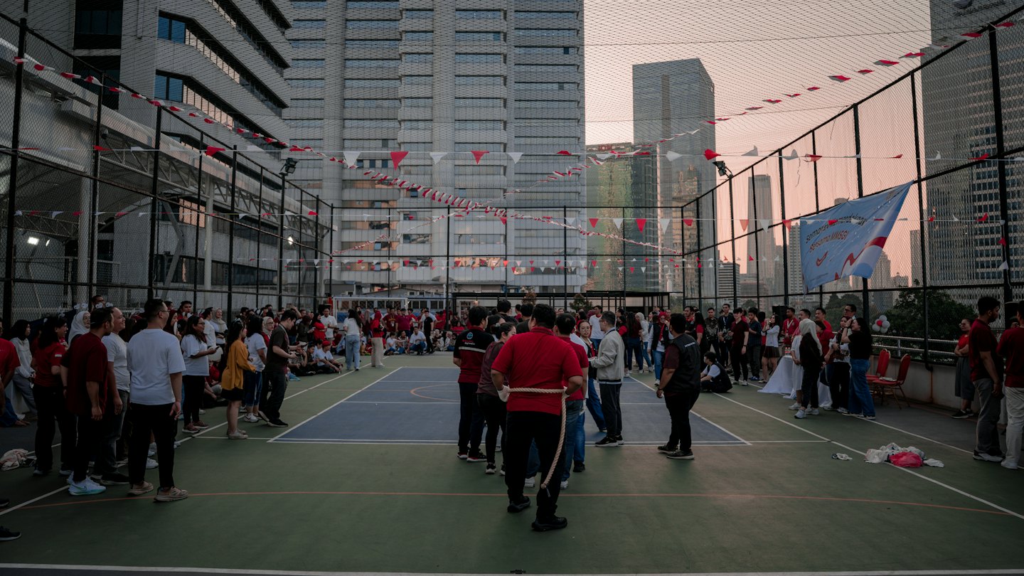 People play tug of war on a rooftop sports court.
