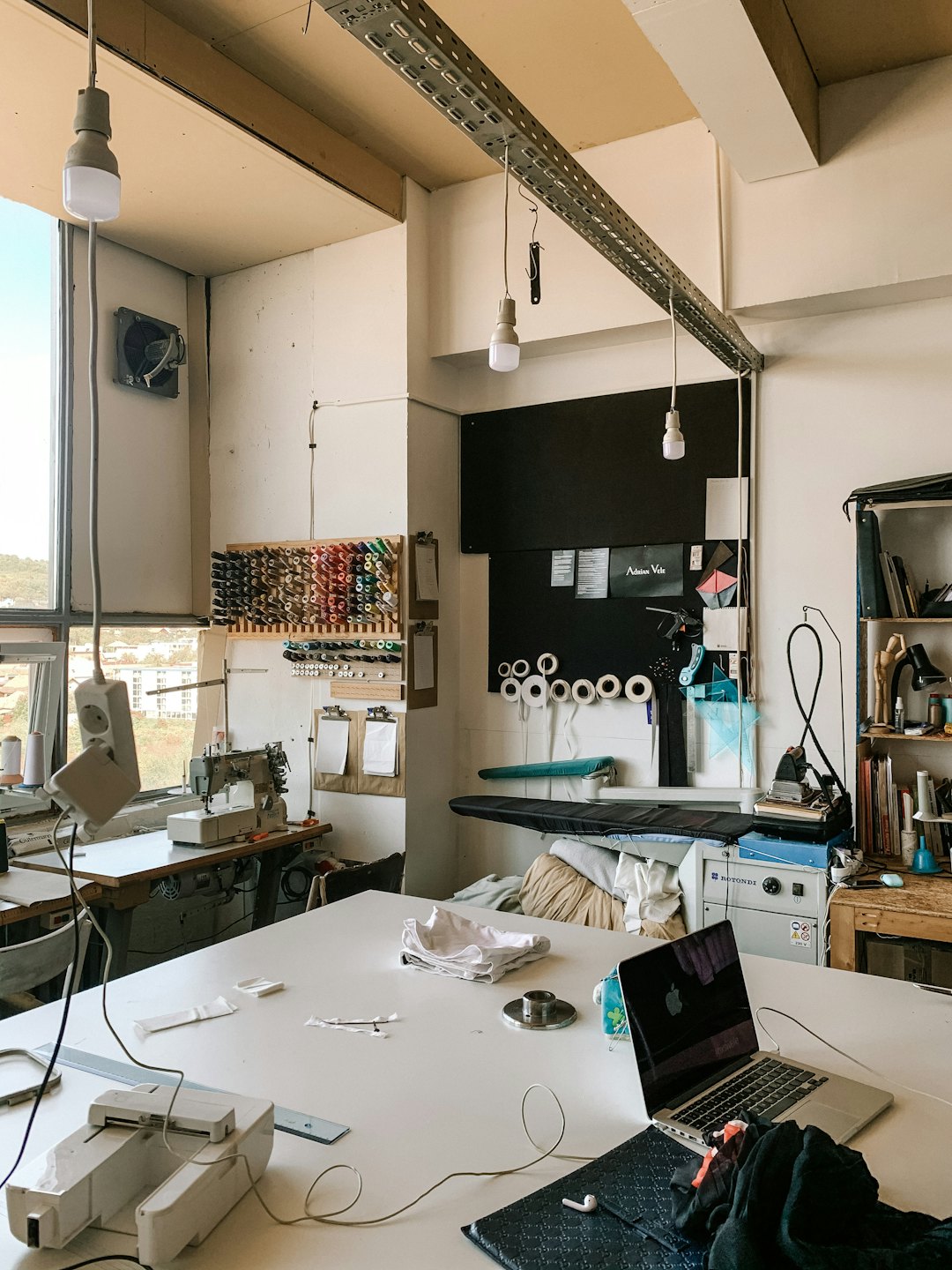 Sewing workshop with an open laptop on a workbench.